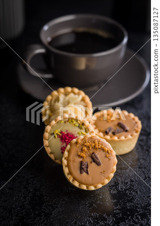 Sweet mini tartlets on black table. 135087127