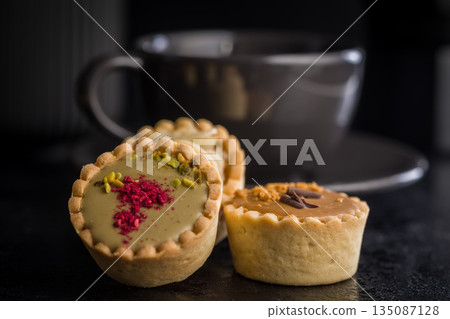 Sweet mini tartlets on black table. Sweet mini tartlets on black table. 135087128