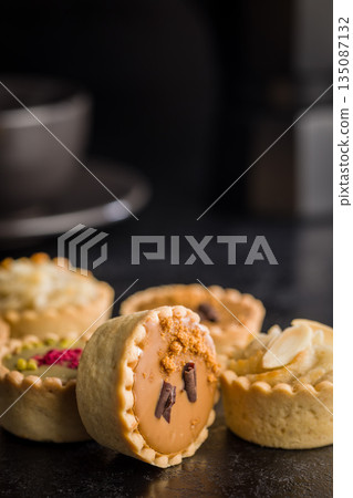 Sweet mini tartlets on black table. Sweet mini tartlets on black table. 135087132