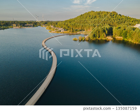 Aerial view of Terhills blue lagoon, green hills, and bike lane tracing the former Eisden coal mine site in Belgium. 135087159