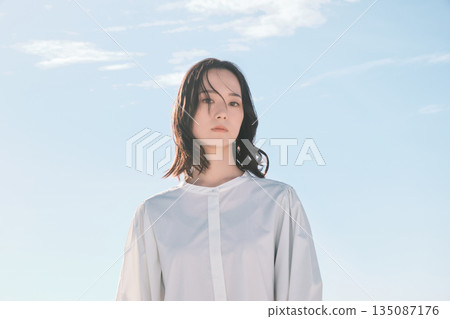 Blue sky background portrait of a young woman 135087176