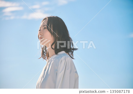 Blue sky background portrait of a young woman 135087178