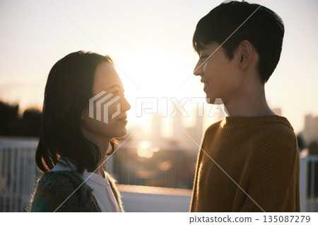 黃昏時分，一對情侶在屋頂上。 135087279