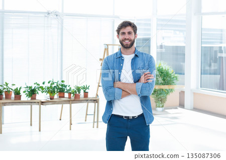 Male wearing denim shirt smiling in creative studio by table with plants, ladder under blinds Male wearing denim shirt smiling in creative studio by table with plants, ladder under blinds 135087306