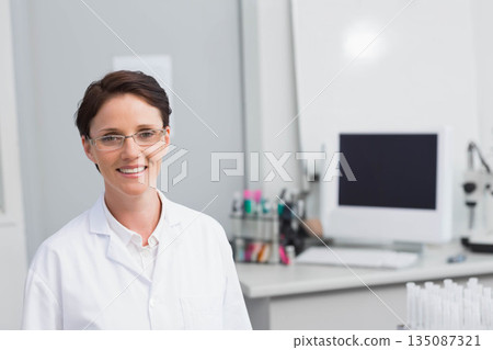Female lab technician standing and smiling at medical lab with computer and microscope, copy space 135087321