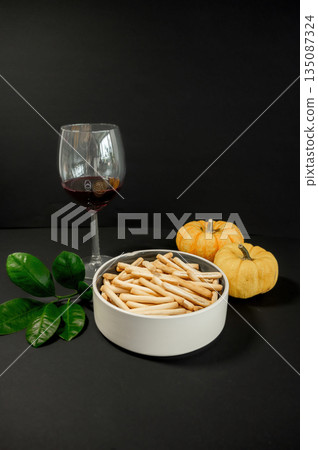 Crispy small breadsticks served on a white glass plate against a black background. Minimalistic food composition highlighting texture, contrast, and simple snack presentation. Crispy small breadsticks served on a white glass plate against a black background. Minimalistic food composition highlighting texture, contrast, and simple snack presentation. 135087324