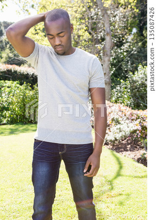African American man standing on backyard lawn surrounded by flowering bushes and trimmed hedges African American man standing on backyard lawn surrounded by flowering bushes and trimmed hedges 135087426