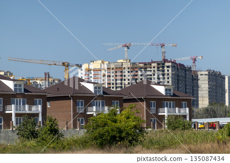 New residential district under construction in Novorossiysk, Russia, with unfinished monolithic apartment buildings and tower cranes against the sky 135087434