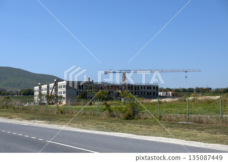 New residential district under construction in Novorossiysk, Russia, with unfinished monolithic apartment buildings, tower cranes and vineyards in the foreground New residential district under construction in Novorossiysk, Russia, with unfinished monolithic apartment buildings, tower cranes and vineyards in the foreground 135087449