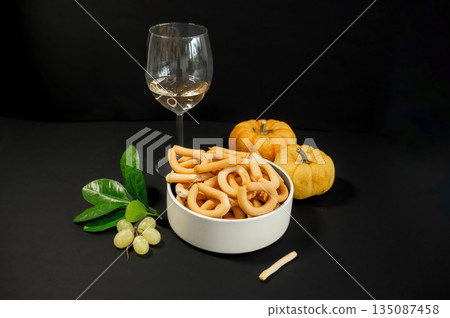 Crispy small breadsticks served on a white glass plate against a black background. Minimalistic food composition highlighting texture, contrast, and simple snack presentation. 135087458