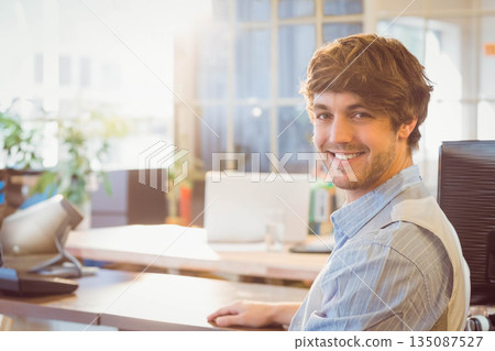 Male professional using telephone while holding glass of water at desk in modern office, copy space 135087527