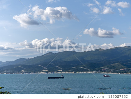 August 24, 2025: Wild beach on the coast of Kabardinka village, Russia, with cliffs, trees and large ships in the background, showcasing coastal landscape and maritime scenery August 24, 2025: Wild beach on the coast of Kabardinka village, Russia, with cliffs, trees and large ships in the background, showcasing coastal landscape and maritime scenery 135087562
