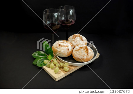 Autumn still life with pumpkins and homemade freshly baked buns arranged on a black background. Warm rustic mood, seasonal harvest, cozy food concept. 135087673