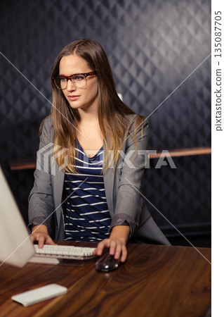 Professional woman working in office, typing on keyboard with monitor, mouse and smartphone 135087705