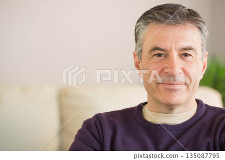 Man sitting on beige sofa in living room wearing purple sweater near potted plant, copy space 135087795
