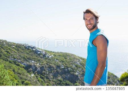 Male wearing blue sleeveless shirt standing on coastal hillside smiling at sea horizon, copy space Male wearing blue sleeveless shirt standing on coastal hillside smiling at sea horizon, copy space 135087805