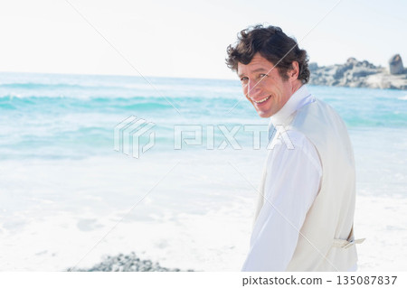 Man wearing white dress shirt and beige vest standing on rocky shoreline, copy space 135087837