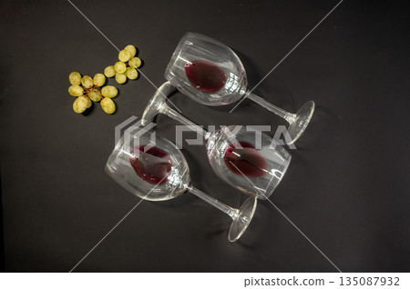 Elegant row of three empty wine glasses on a black background. Minimalistic, reflective glassware composition with clean lines and moody lighting. Perfect for wine, bar, and restaurant concepts. 135087932