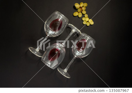 Elegant row of three empty wine glasses on a black background. Minimalistic, reflective glassware composition with clean lines and moody lighting. Perfect for wine, bar, and restaurant concepts. Elegant row of three empty wine glasses on a black background. Minimalistic, reflective glassware composition with clean lines and moody lighting. Perfect for wine, bar, and restaurant concepts. 135087967