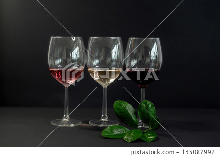 Elegant row of three empty wine glasses on a black background. Minimalistic, reflective glassware composition with clean lines and moody lighting. Perfect for wine, bar, and restaurant concepts. Elegant row of three empty wine glasses on a black background. Minimalistic, reflective glassware composition with clean lines and moody lighting. Perfect for wine, bar, and restaurant concepts. 135087992