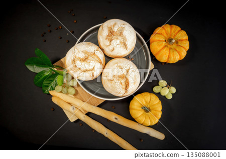 Autumn still life with pumpkins and homemade freshly baked buns arranged on a black background. Warm rustic mood, seasonal harvest, cozy food concept. Autumn still life with pumpkins and homemade freshly baked buns arranged on a black background. Warm rustic mood, seasonal harvest, cozy food concept. 135088001
