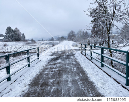 Road across a snow-covered bridge in winter in cloudy weather Road across a snow-covered bridge in winter in cloudy weather 135088995