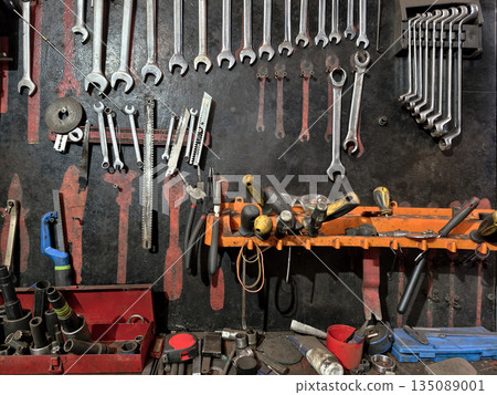 A wall filled with various hand tools in a garage shows wrenches, screwdrivers, and other items used for fixing or maintaining vehicles and equipment A wall filled with various hand tools in a garage shows wrenches, screwdrivers, and other items used for fixing or maintaining vehicles and equipment 135089001