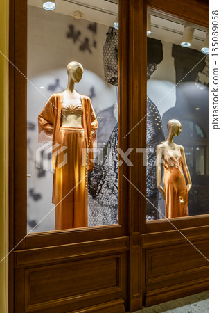 Elegant Orange Satin Dress on a Gold Mannequin in a Boutique Window Display 135089058