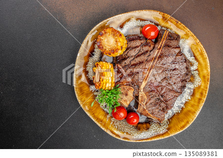 Grilled T-bone steak with corn on the cob, cherry tomatoes, and fresh herbs on a ceramic plate. copy space, top view Grilled T-bone steak with corn on the cob, cherry tomatoes, and fresh herbs on a ceramic plate. copy space, top view 135089381