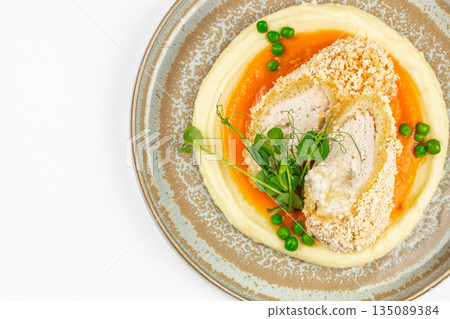 Breaded chicken roulade with mashed potatoes, carrot puree, green peas, and microgreens on a ceramic plate. copy space, top view Breaded chicken roulade with mashed potatoes, carrot puree, green peas, and microgreens on a ceramic plate. copy space, top view 135089384