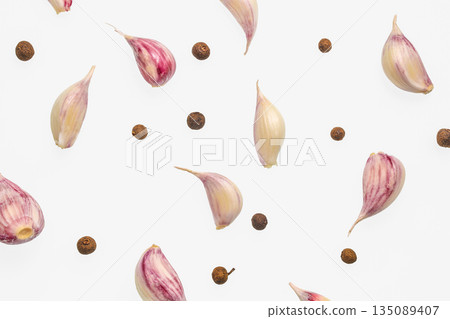 Garlic cloves and peppercorns scattered on white background, top view Garlic cloves and peppercorns scattered on white background, top view 135089407