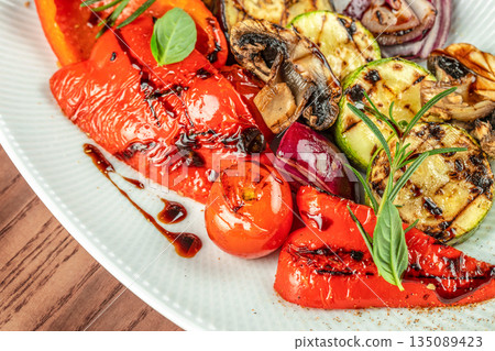 Grilled vegetables with balsamic glaze and fresh herbs on a white plate. top view. copy space 135089423
