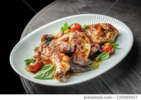 Roasted chicken with herbs and cherry tomatoes on a white plate Roasted chicken with herbs and cherry tomatoes on a white plate 135089427