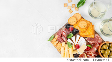 Antipasto platter with assorted cheeses, cured meats, crackers, olives, figs, and berries on a wooden serving board, top view, copy space Antipasto platter with assorted cheeses, cured meats, crackers, olives, figs, and berries on a wooden serving board, top view, copy space 135089441