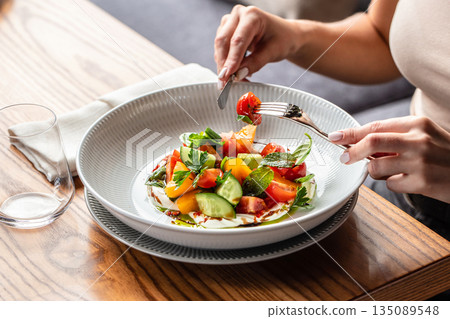 Fresh vegetable salad with tomatoes, cucumbers, herbs, and yogurt dressing in a bowl 135089548