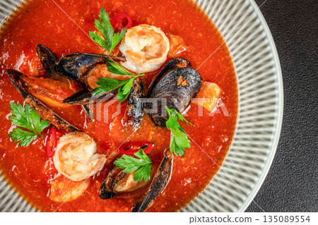Seafood soup with shrimp, mussels, and fresh herbs in a spicy tomato broth 135089554