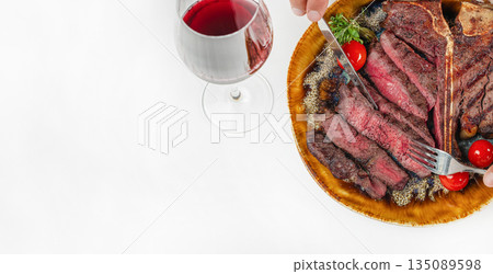 Juicy T-bone steak with glass of red wine on white background. top view. copy space Juicy T-bone steak with glass of red wine on white background. top view. copy space 135089598