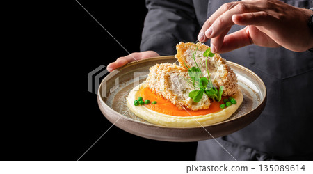 chef hands with Breaded chicken roll with mashed potatoes and carrot puree on a plate. copy space chef hands with Breaded chicken roll with mashed potatoes and carrot puree on a plate. copy space 135089614