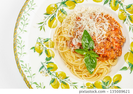 Spaghetti with bolognese sauce and parmesan cheese on a decorated plate. top view 135089621