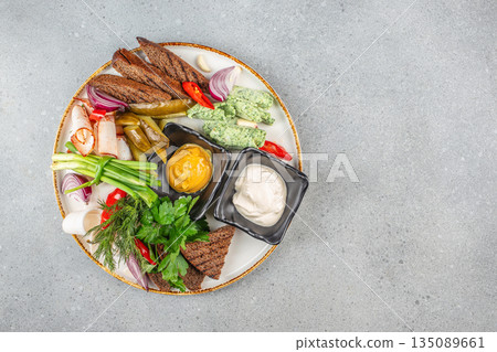 Traditional assorted snack platter with rye bread, pickles, mustard, creamy dips, herbs, onion, garlic, and spiced meat slices 135089661