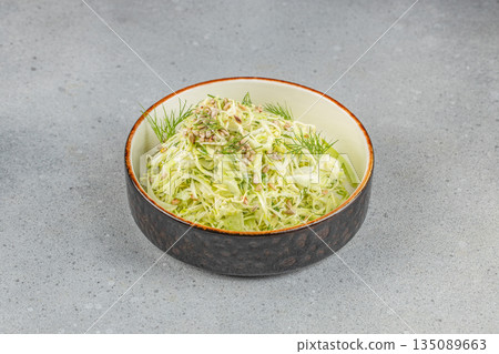 Fresh cabbage salad with shredded greens, dill, sunflower seeds, and light dressing served in a rustic ceramic bowl 135089663