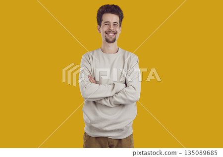 Portrait of happy smiling brunet guy in beige sweatshirt on yellow background looking at camera. Portrait of happy smiling brunet guy in beige sweatshirt on yellow background looking at camera. 135089685