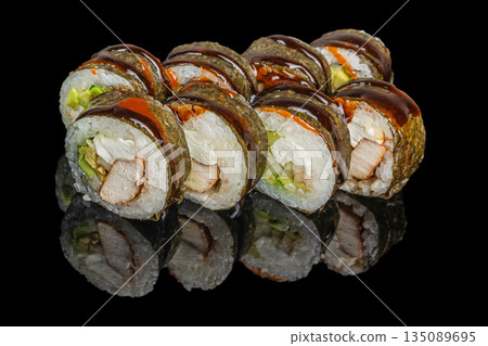 Sushi rolls with chicken, cream cheese, avocado, and vegetables wrapped in seaweed and drizzled with dark sauce are beautifully arranged on a reflective black surface 135089695