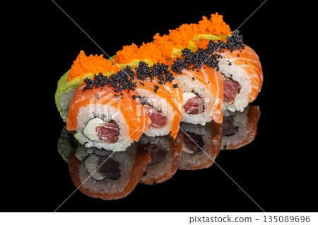 Colorful sushi rolls topped with salmon, avocado, black and orange tobiko, filled with tuna and cream cheese, are arranged in a neat row on a reflective black background 135089696