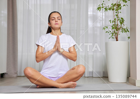Woman practicing yoga mindfulness with eyes closed and hands in namaste mudra 135089744