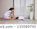 Mother and daughter bonding during child's pose on a yoga mat 135089745