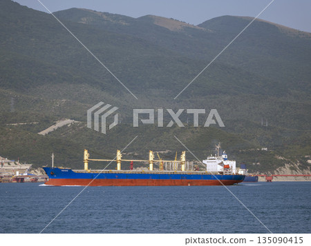 August 12, 2025: Cargo ship Yeditepe entering the port of Novorossiysk, Russia, with mountains in the background 135090415