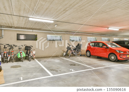 A well-organized urban parking area featuring several bicycles along with parked cars, showcasing efficient use of space in a commercial setting. 135090616