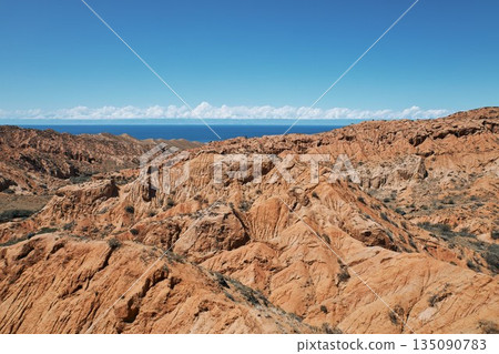 Layered clay sandstone hills and valleys in a desolate landscape with blue sky Layered clay sandstone hills and valleys in a desolate landscape with blue sky 135090783