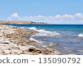 Rocky shoreline of a lake with waves gently breaking onto irregular stone beach 135090792